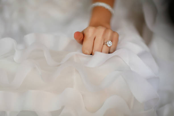 Bride's hand with beautiful diamond ring on white dress